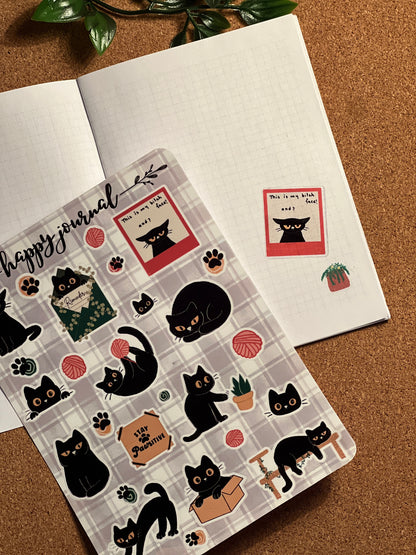Sheet of cat-themed stickers with a 'happy journal' design on a brown surface.